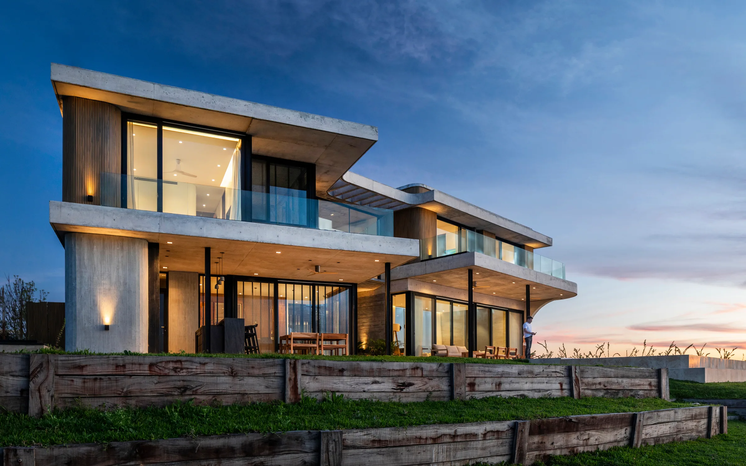 Vivienda contemporánea al atardecer con cerramientos vidriados de piso a techo